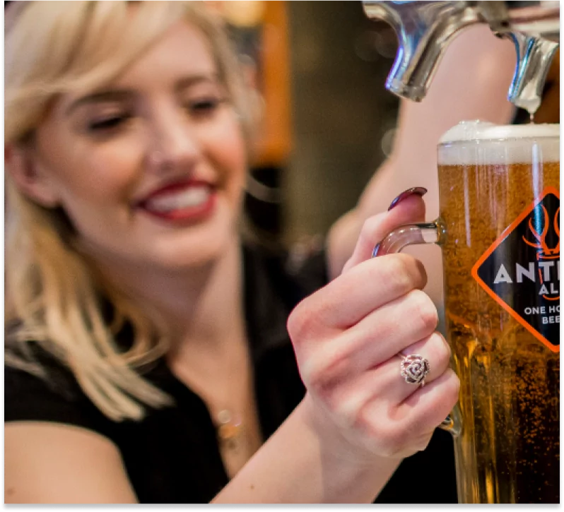 A bartender smiles while pouring a glass of Antler Ale at Mr MIKES Steakhouse.