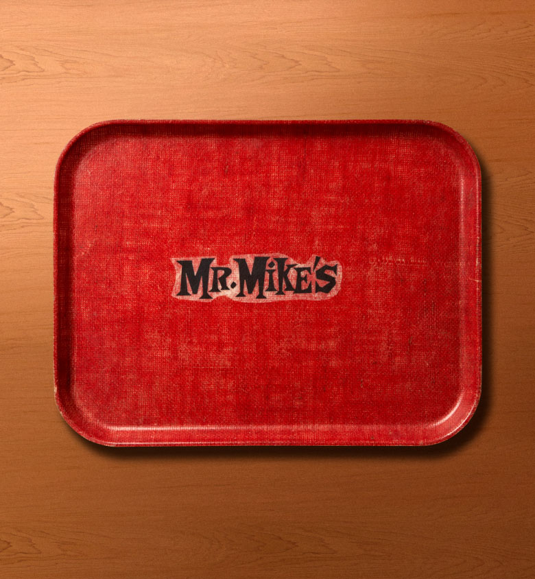 Red serving tray with the MR MIKES logo in black, placed on a wooden surface.